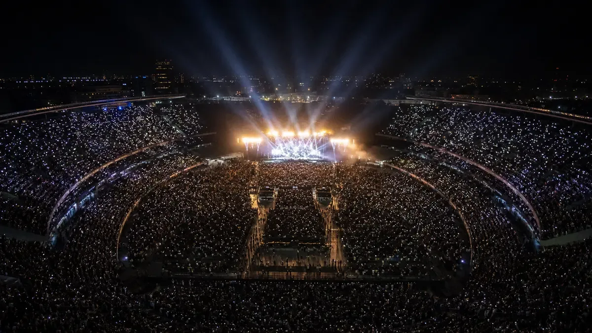 Estadio lleno visto desde lo alto durante un recital nocturno
